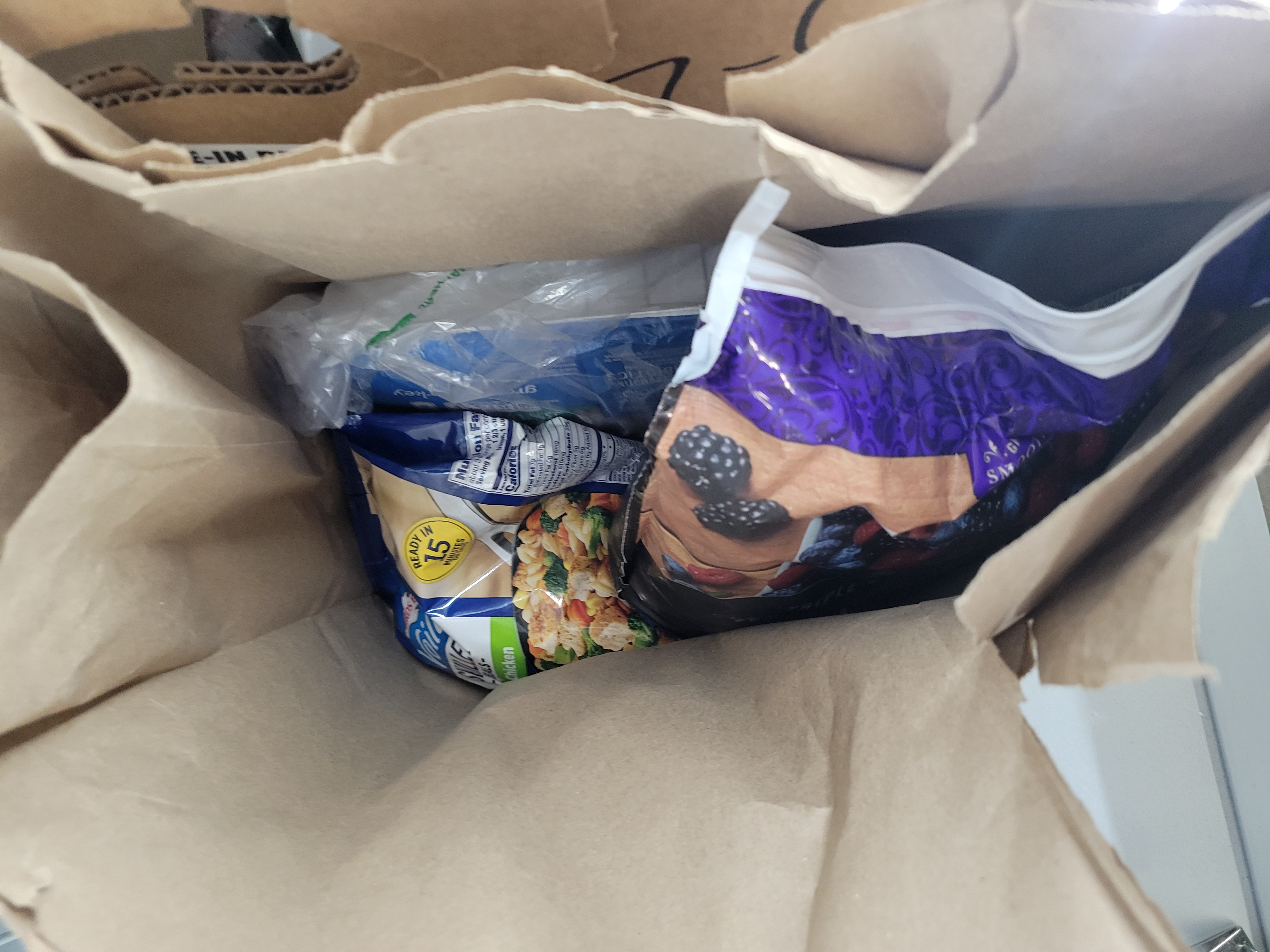 Bag of berries and bag of chicken skillet meal in a paper bag in a banana box.